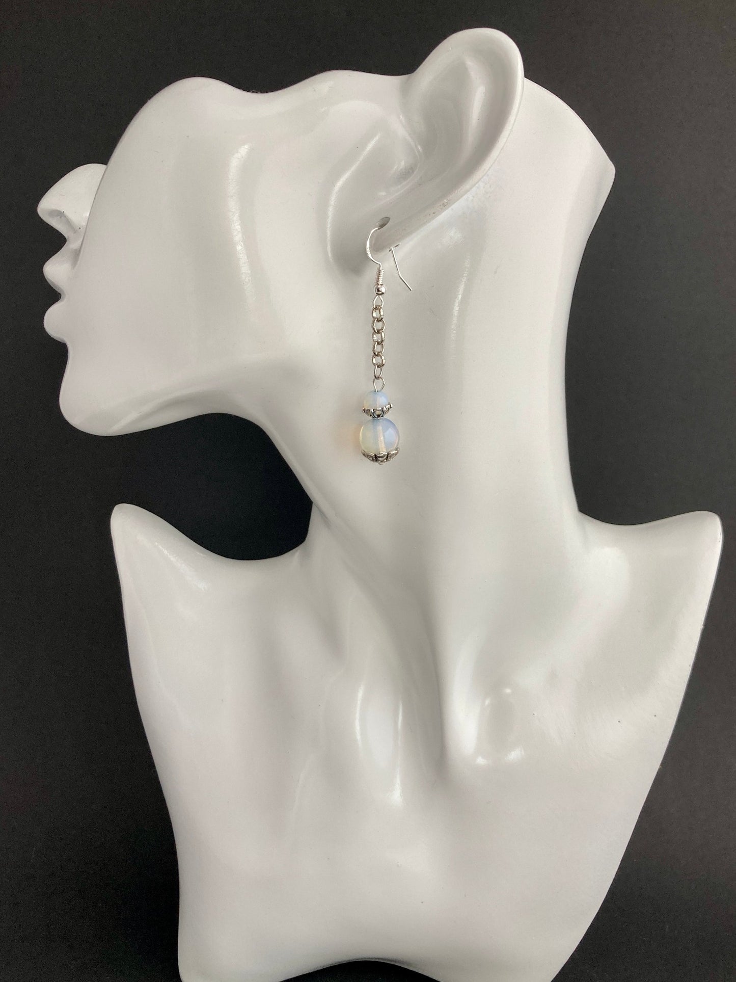 These semi-precious stone earrings are simple and feminine with a little swag. A Classic but Contemporary look. They can be dressed up for a Sunday Service or dressed down with your favorite jeans. Two frosted white beads in 2 different sizes, on a single stainless steel chain. Approximately, 2 1/2" long with a Sterling silver ear wire. For a great price & a charming look - these are winners! 
