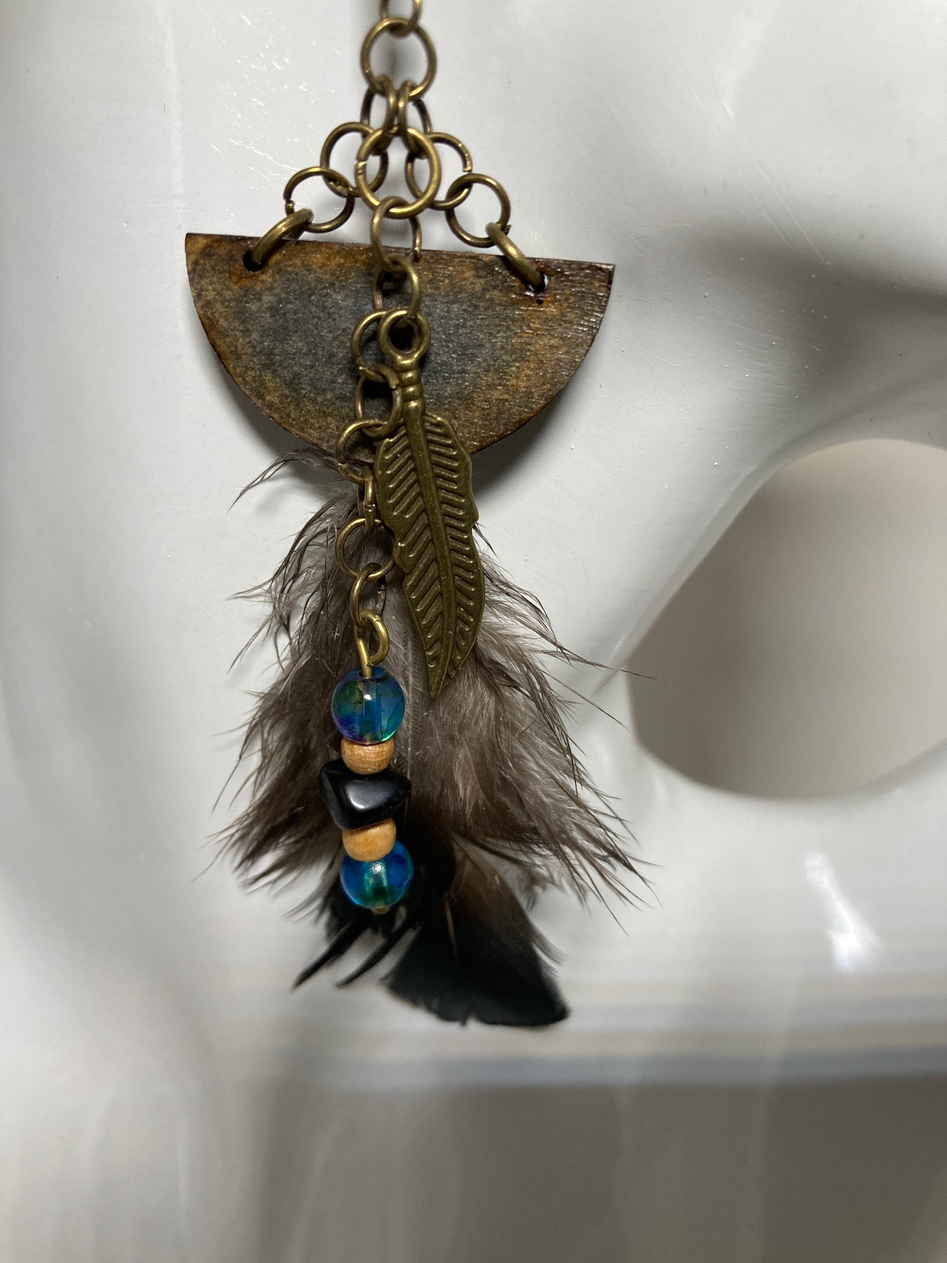 This smoky looking pair will put you in a sexy &amp; fun-loving mood. Nature inspired with a stained half moon wooden slice, an alloy bronze metal leaf, coordinating glass beads, small chain links and finished with (hypoallergenic) ear wires. both the slice and the actual feather have iridescent colors which definitely elevate the design.