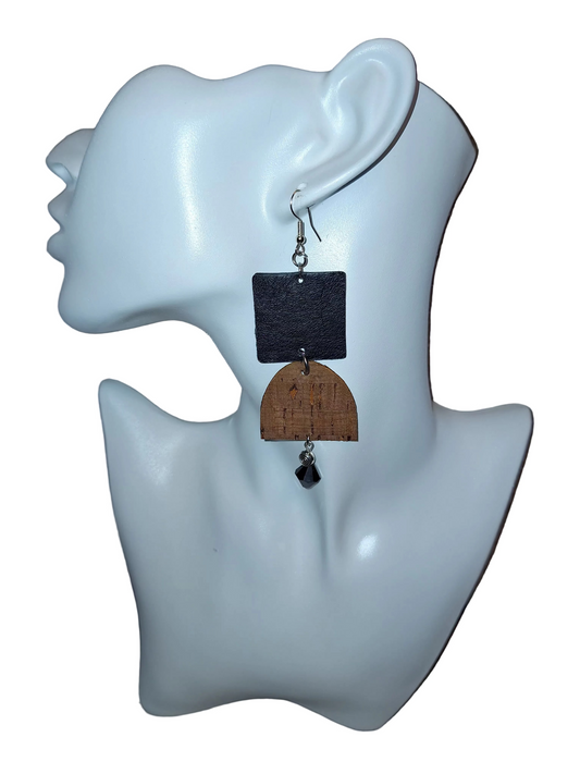  A textured black square paired with a curved brown cork accent, silver bead, and black glass drop on a white mannequin head. Crafted with hypoallergenic ear wires for comfort and designed to be an affordable everyday staple at $15.00.