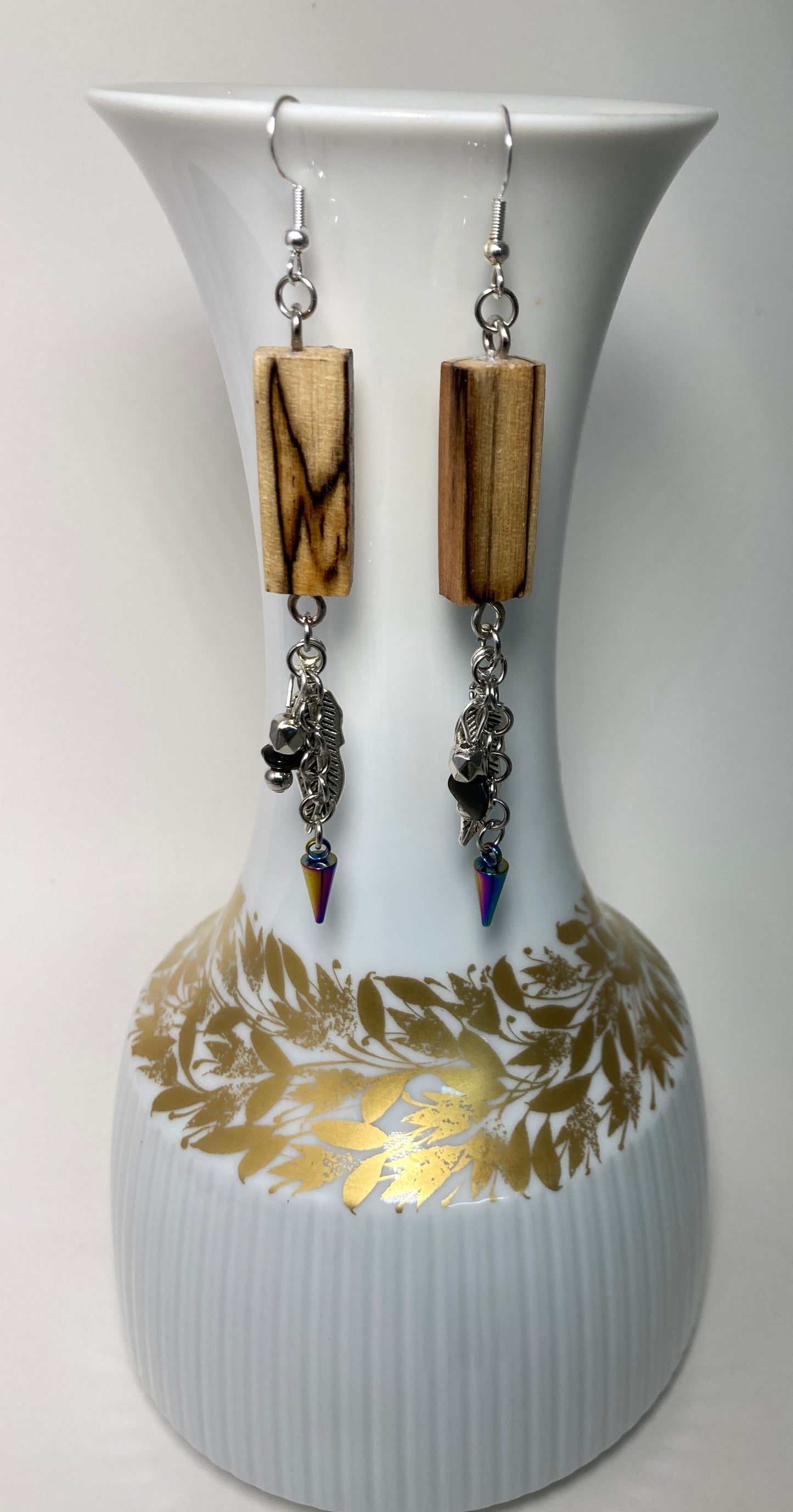 This pair of earrings deserve to be named for the awesome human who was the inspiration for our Spalted Birchwood line of jewelry. Measuring 1/2" x 1" (the wood portion) plus 1 1/4 (the Stainless steel chain and charms). Finished with a Sterling Silver ear wire. This design is a definite attention grabber. A win - win at $24.95.