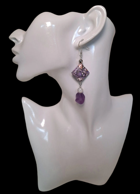 The design includes 1 diamond shaped soft purple printed earring with a marbleized look, 1 coordinating frosted bead in a matt finish, 1 cracked glass and 1 silver bead.
Measuring approx.&nbsp; 2" not including the Sterling silver ear wires.&nbsp;