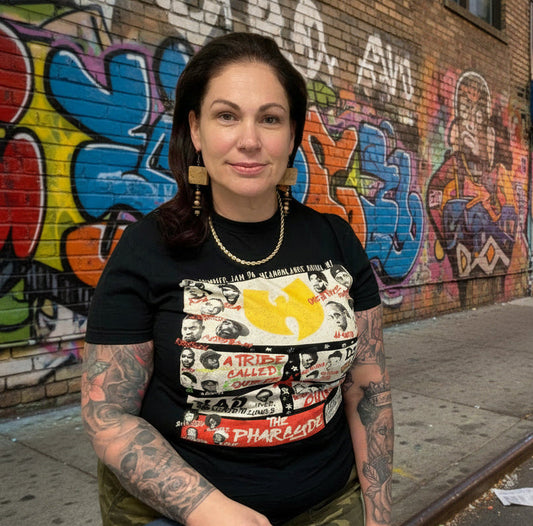 Woman wearing a graphic t-shirt in front of a colorful graffiti wall. Wearing  rustic block and bead earrings.